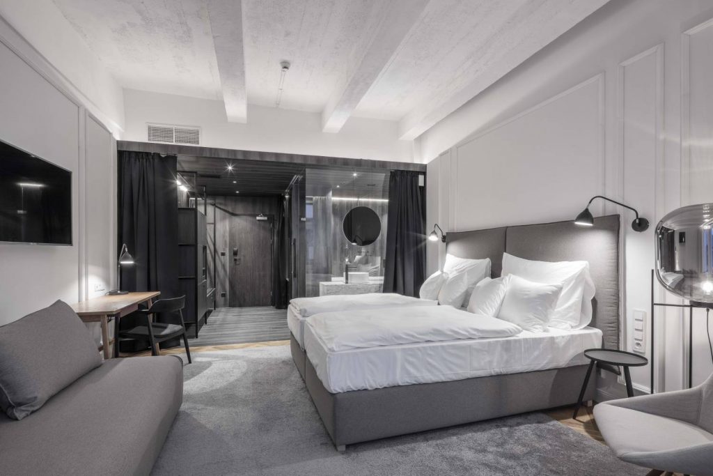 designový hotelový pokoj s velkou postelí a prosklenou koupelnou