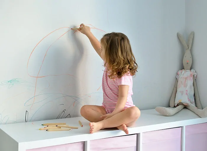 holčička si hraje s pastelkami a kreslí po zdech